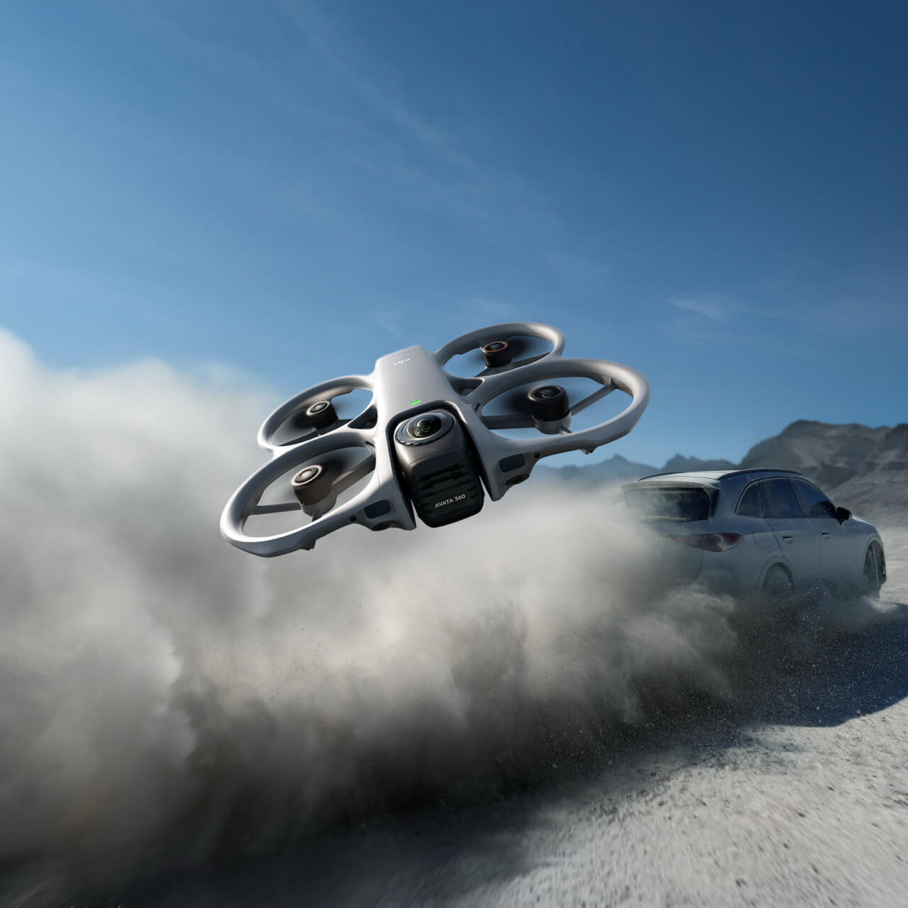 Drone flying over a car on a desert road with mountains in the background